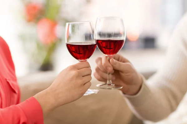 Manos de pareja tintineando copas de vino tinto — Foto de Stock