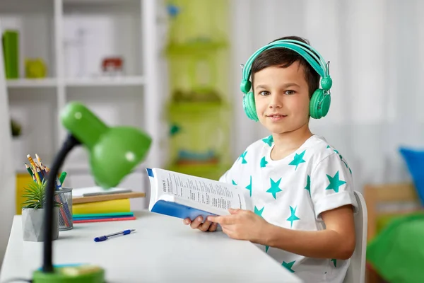 童年和技术概念 快乐小学生在家里的耳机阅读书 — 图库照片