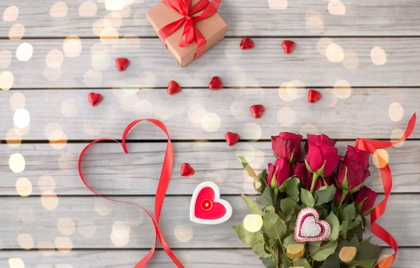 Close up of red roses, gift, candies and candle — Stock Photo, Image