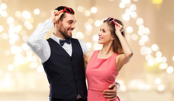 バレンタインの日 愛と人コンセプト お祝いライト ベージュの背景の上のハート型サングラスで幸せなカップル — ストック写真