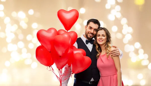 Feliz pareja con globos en forma de corazón rojo —  Fotos de Stock