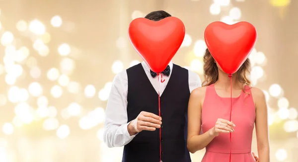 Paret gömmer sig bakom röda Hjärtformade ballonger — Stockfoto