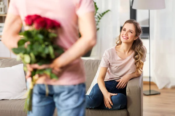 Vrouw op zoek naar man met bos bloemen thuis — Stockfoto