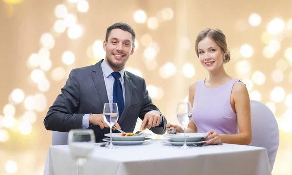 Smiling couple eating appetizers at restaurant — Stock Photo, Image