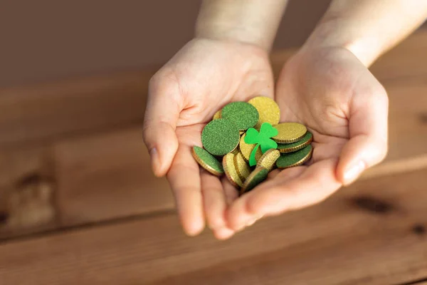 Manos con monedas de oro y hoja de trébol — Foto de Stock