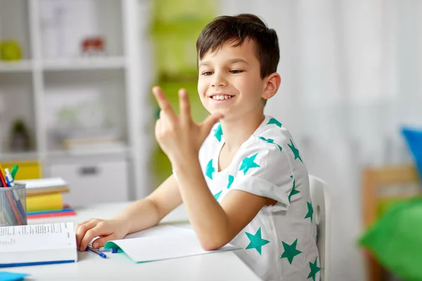 Junge macht Hausaufgaben und zählt mit den Fingern — Stockfoto