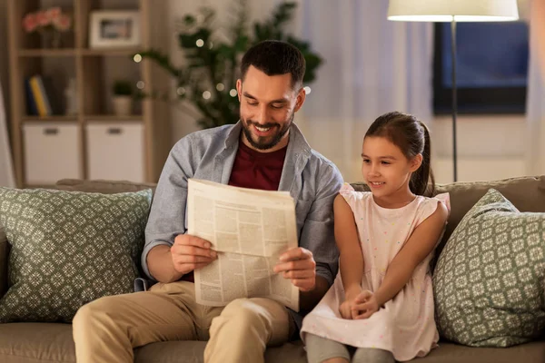 Father reading newspaper to daughter at home — Stock Photo, Image