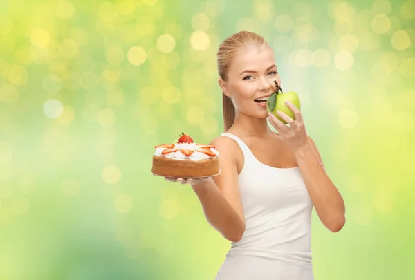 Glückliche Frau isst Apfel statt Kuchen — Stockfoto