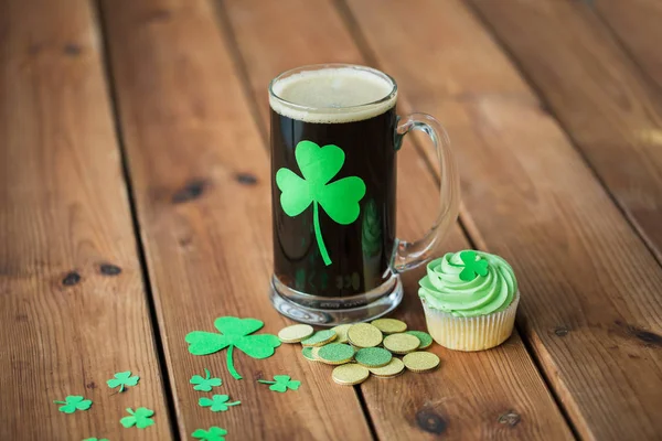 Shamrock sur verre de bière, cupcake vert et pièces — Photo