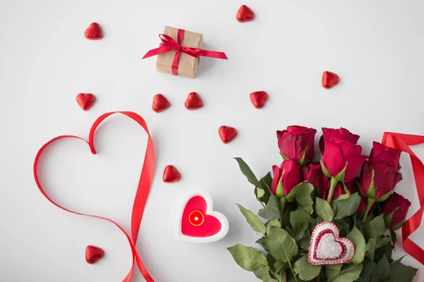 Close up de rosas vermelhas, presente, doces e vela — Fotografia de Stock
