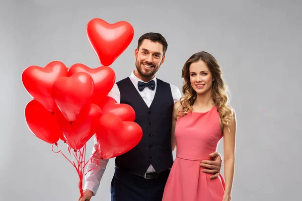 Coppia felice con palloncini a forma di cuore rosso — Foto Stock