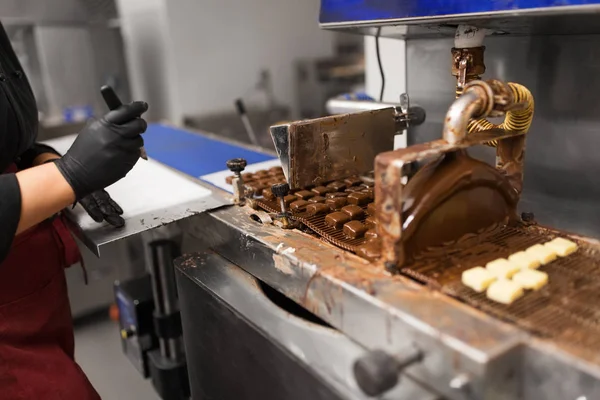 stock image production, candy shop and people concept - confectioner making candies by chocolate coating machine at confectionery