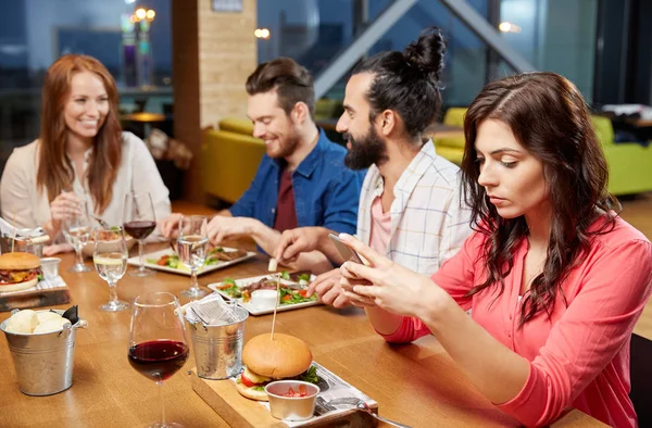 Verveeld vrouw berichten op smartphone bij restaurant — Stockfoto