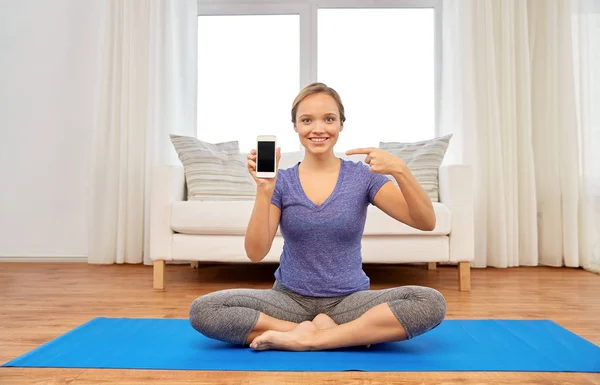 Mulher com smartphone fazendo ioga em casa — Fotografia de Stock