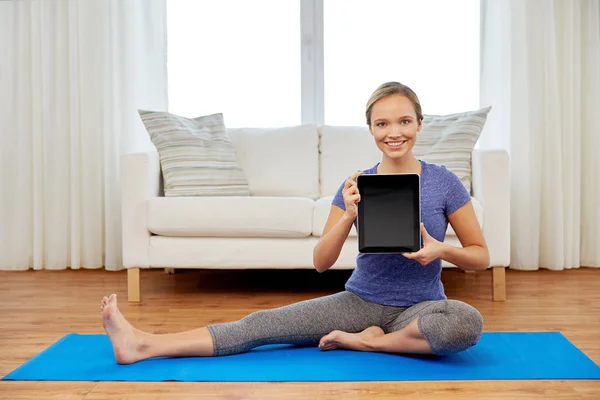 Woman with tablet computer doing yoga at home — Stock Photo, Image