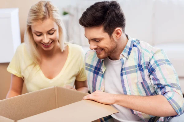 Glückliches Paar schaut in Karton oder Paket zu Hause — Stockfoto
