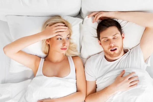 Unhappy woman in bed with snoring sleeping man — Stock Photo, Image