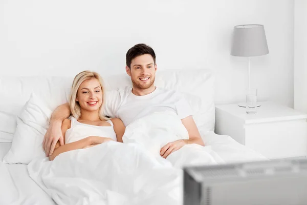 幸福的夫妇在家里的床上躺着看电视 — 图库照片