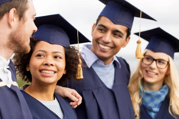 Happy students or bachelors in mortar boards — Stock Photo, Image