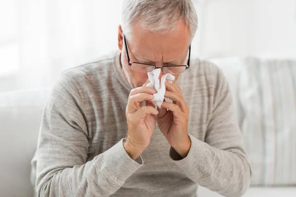 Zieke senior man met papieren doekje blazen zijn neus — Stockfoto