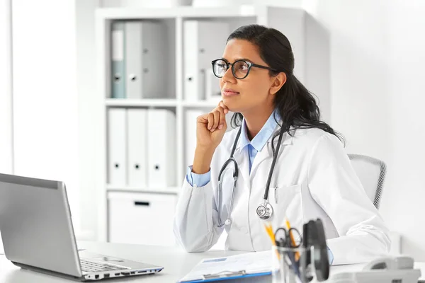 Vrouwelijke arts met laptop en papieren in ziekenhuis — Stockfoto