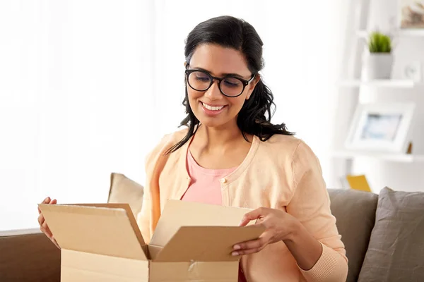 Счастливая индийская женщина открывает коробку для посылок дома — стоковое фото