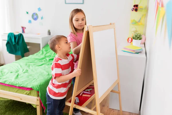 Bambini felici che disegnano su cavalletto o flip board a casa — Foto Stock