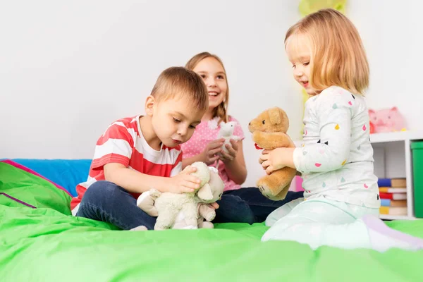 Счастливые дети играют с мягкими игрушками дома — стоковое фото