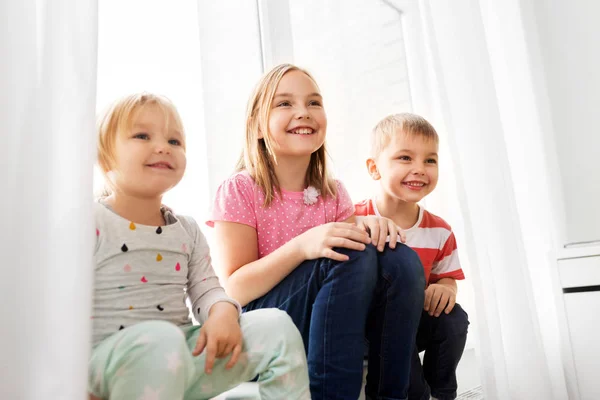 Happy little kids sitting on window sill — Stock Photo, Image