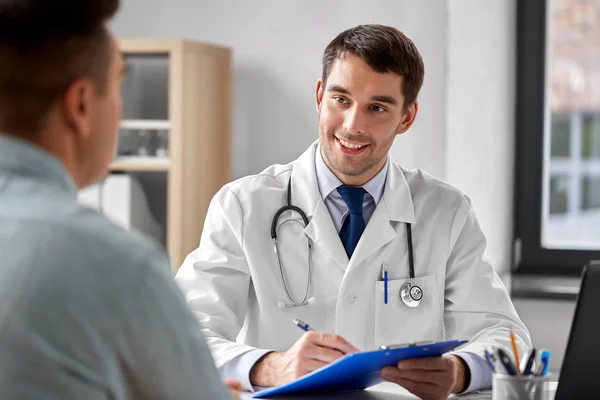 Médecin avec presse-papiers et patient masculin à l'hôpital — Photo