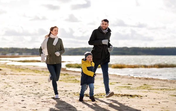 Gelukkige familie loopt langs herfst strand — Stockfoto