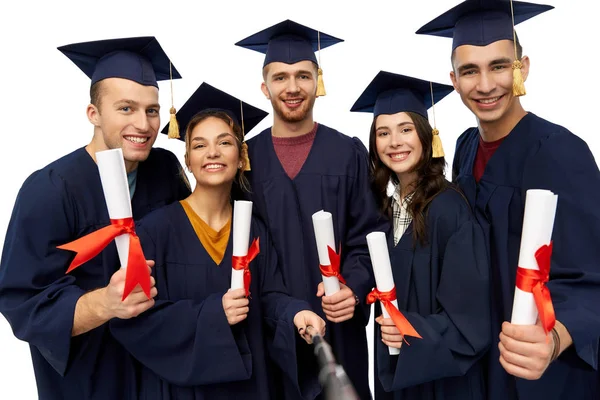 Happy graduates with diplomas taking selfie — Stock Photo, Image