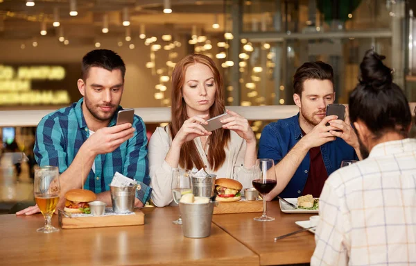 Amigos com smartphones no restaurante — Fotografia de Stock