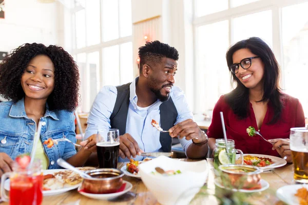 Amigos felices comiendo y hablando en el restaurante —  Fotos de Stock