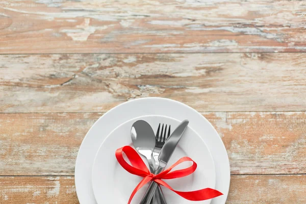 在一套盘子上用红色丝带系上的餐具 — 图库照片