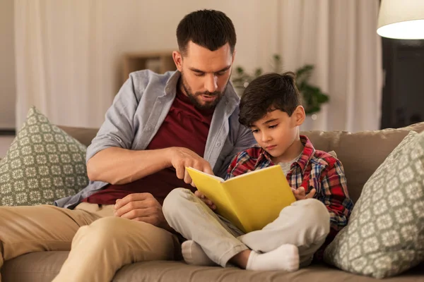 Father and son reading book sofa at home — Stock Photo, Image