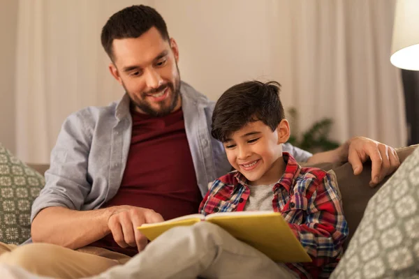 Happy father and son reading book sofa at home — Stock Photo, Image