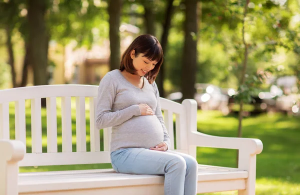 Feliz grávida asiático mulher sentado no parque banco — Fotografia de Stock