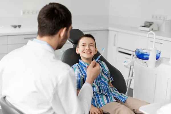 医療コンセプト 歯科医院で子供の患者さんに歯ブラシを与えて男性歯科医 — ストック写真