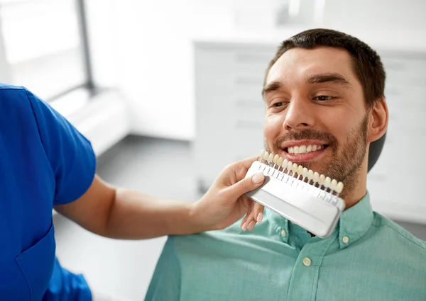 Dentista escolhendo a cor do dente para o paciente na clínica — Fotografia de Stock