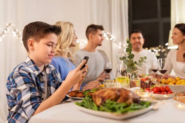 Menino com smartphone na festa de jantar de família — Fotografia de Stock