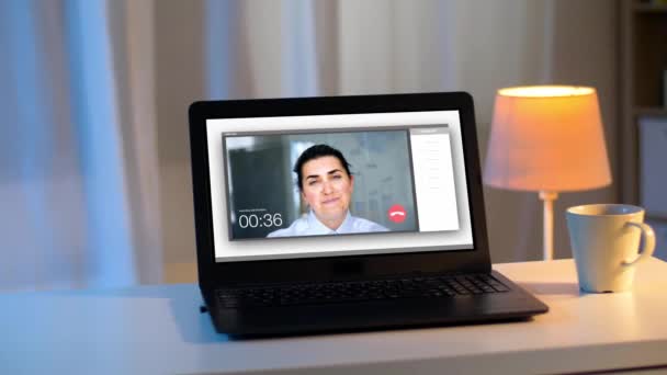 Ноутбук с видеозвонком на экране на столе ночью — стоковое видео