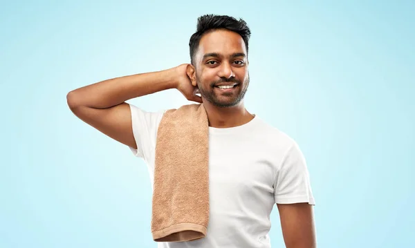 Улыбающийся индиец с полотенцем на синем фоне — стоковое фото