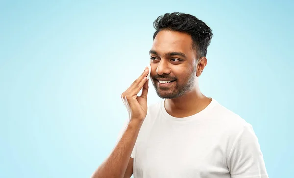 Lächelnder indischer Mann reinigt Gesicht mit Wattepad — Stockfoto