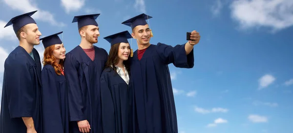 Graduates taking selfie by smartphone — Stock Photo, Image