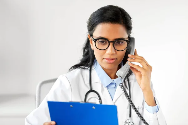 Läkare med Urklipp ringa på telefon på sjukhus — Stockfoto