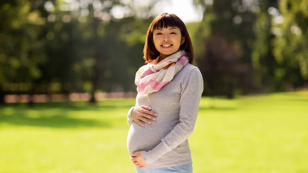 Счастливая беременная женщина в парке — стоковое фото