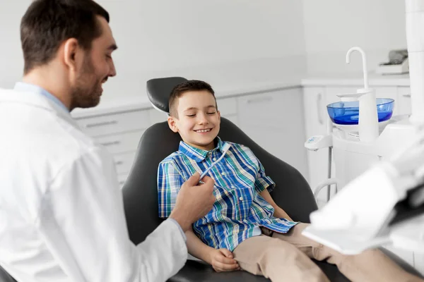 Dentista dándole cepillo de dientes a un paciente infantil en la clínica — Foto de Stock