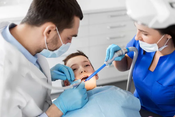 Dentista tratar dentes de criança na clínica odontológica — Fotografia de Stock