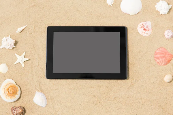 Tablet computer e conchiglie sulla sabbia della spiaggia — Foto Stock
